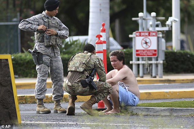 Security forces attend to an unidentified male outside the the main gate at Joint Base Pearl Harbor-Hickam, Wednesday, following a shooting which killed two civilians